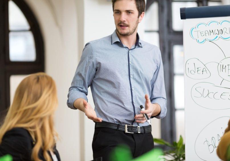 Business person holding presentation, gesturing, rolled up sleeves